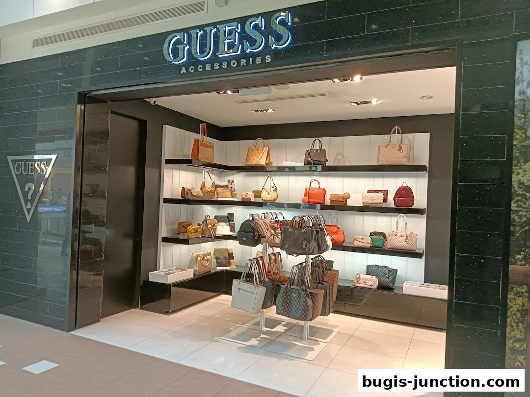 The entrance of a GUESS ACCESSORIES shop displaying various handbags on shelves.