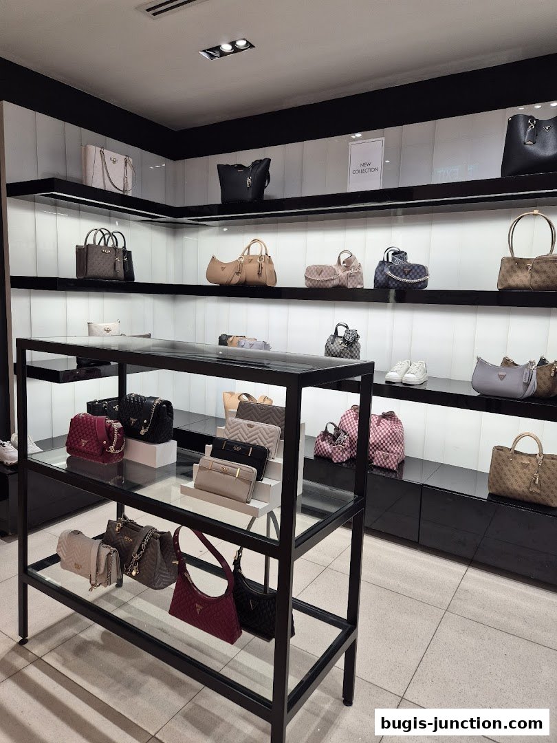 A display of various Guess handbags and accessories on shelves and a black metal rack.