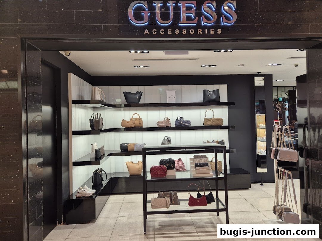 The entrance of a GUESS ACCESSORIES shop showcasing various handbags and accessories on display shelves.