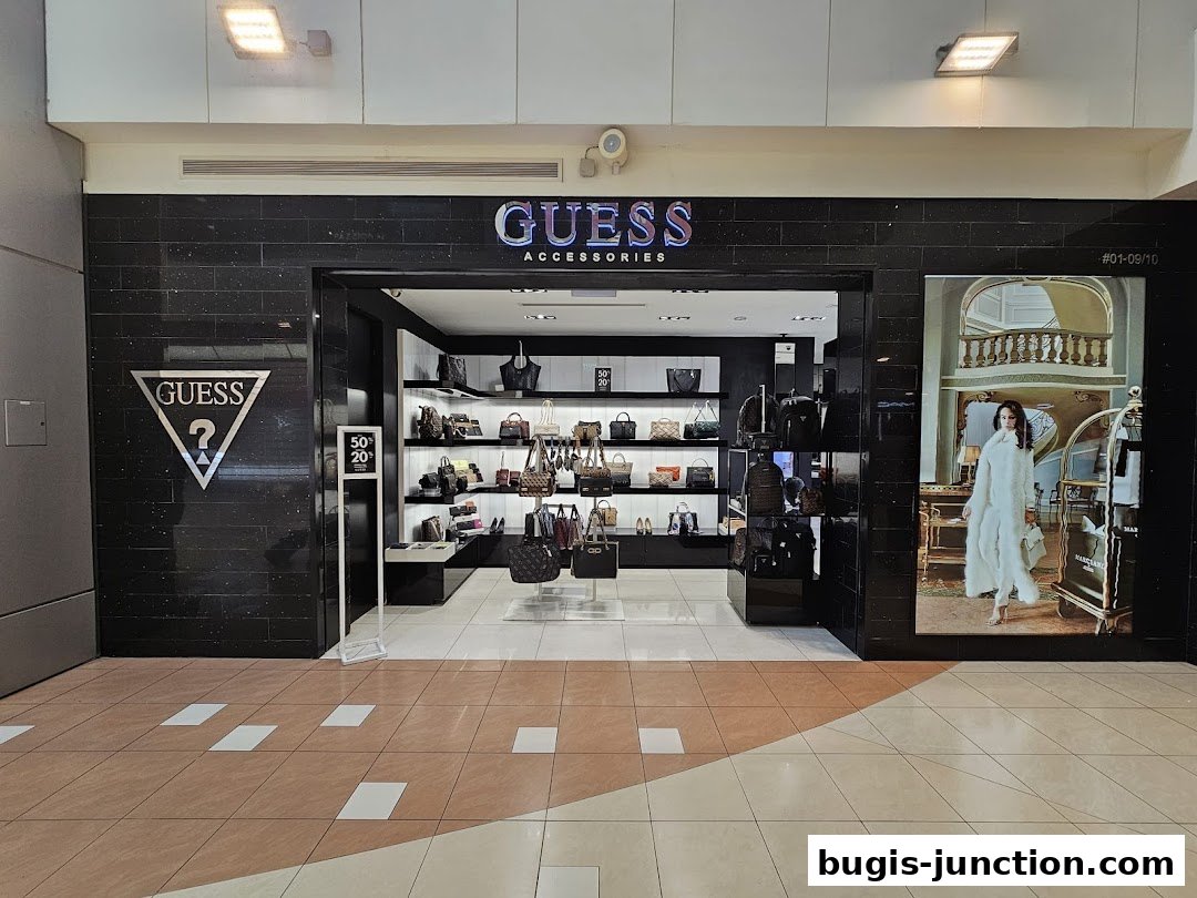 The Guess Accessories shop front displays a wide selection of handbags and accessories on shelves.