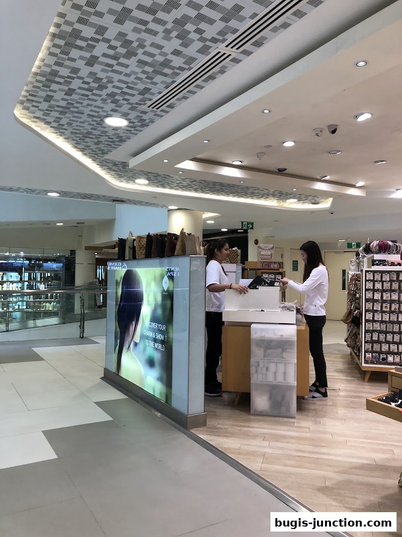 Two women are standing at a counter in a retail store, with merchandise displayed around them.