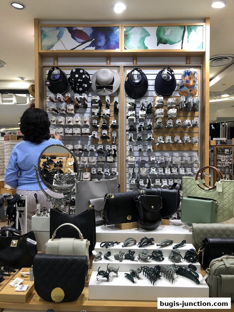 A woman browses a display of handbags and hair accessories in a retail store.