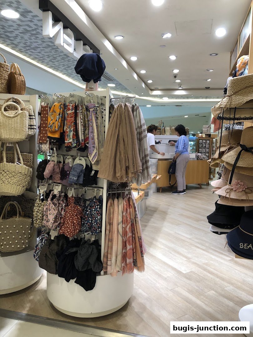 Interior of a fashion accessories shop displaying scarves, bags, and hats.