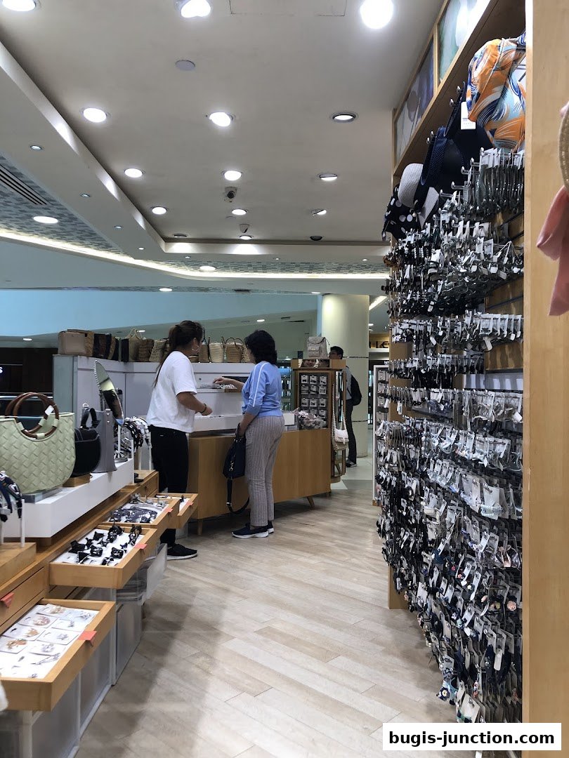 Customers browsing accessories and bags in a well-lit retail store.