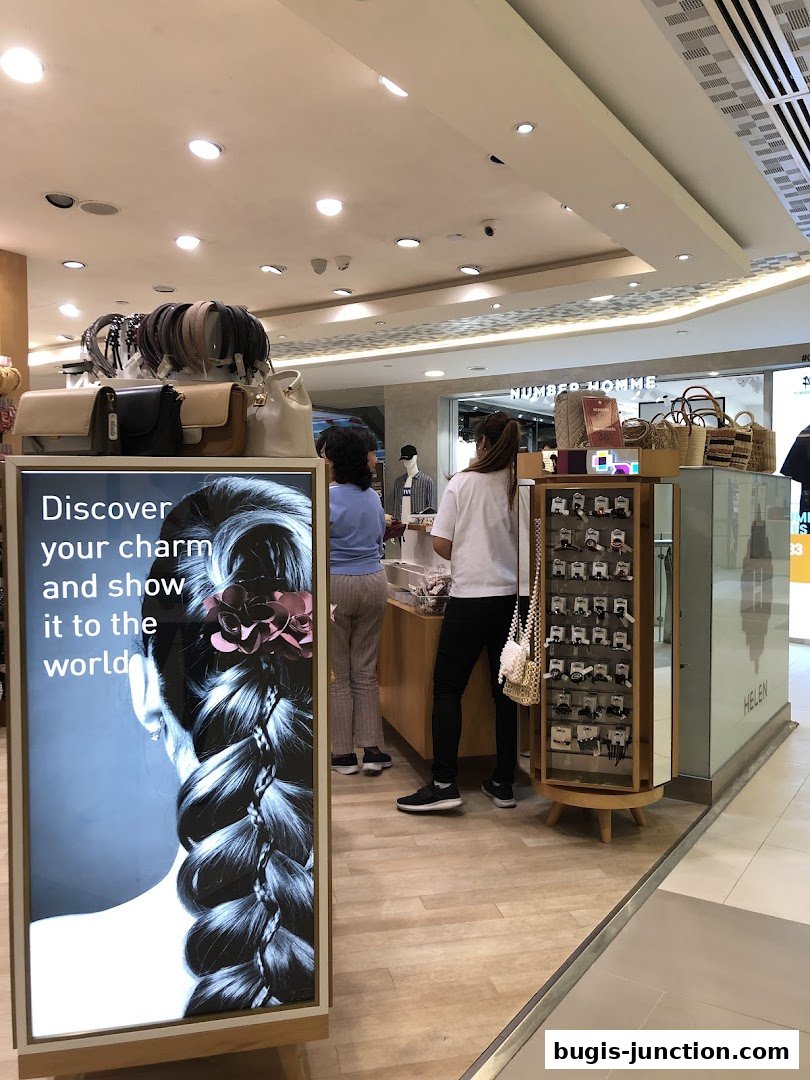 Shop interior with customers browsing accessories and a display featuring a braided hairstyle.