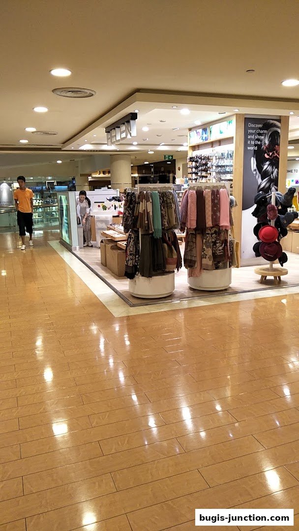 A retail shop interior with clothing displays and accessories, including scarves and hats.