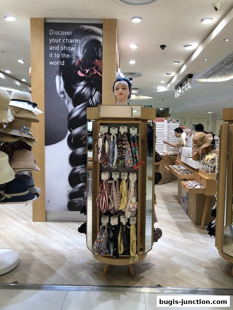 A shop interior displaying hats and hair accessories with a large promotional poster.