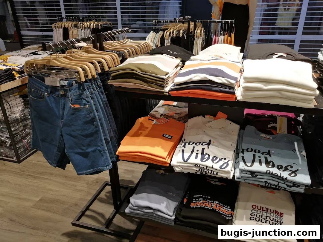 A retail shop display featuring folded t-shirts and denim shorts on hangers.