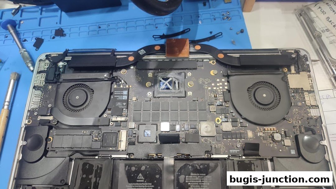A disassembled laptop motherboard with fans, chips, and battery visible.