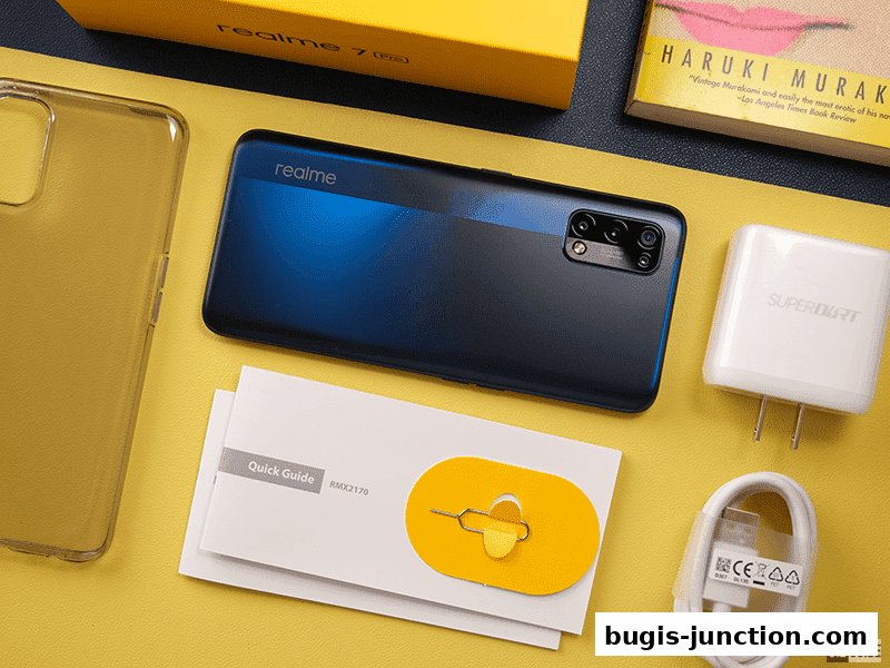 A Realme 7 Pro smartphone with accessories, a charger, and a book are displayed.