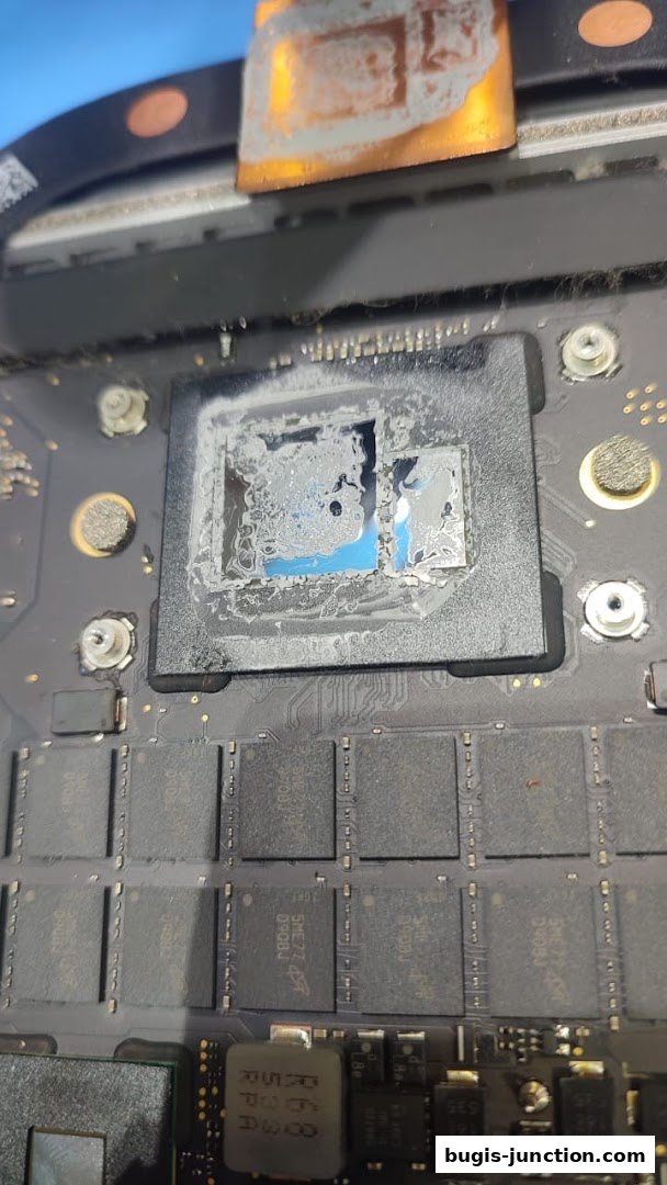 Close-up of a damaged computer chip with thermal paste residue on a circuit board.