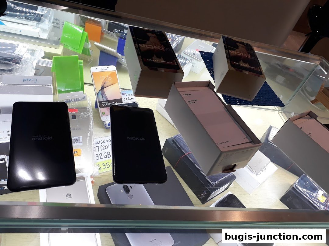 Display case filled with various mobile phones and their packaging, including Nokia and Samsung models.
