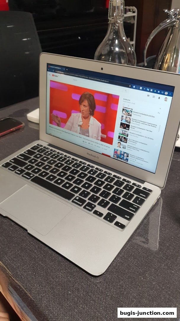 A MacBook Air laptop displaying a YouTube video of a talk show.