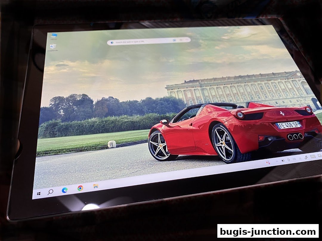 A tablet displays a red convertible sports car parked in front of a grand building.