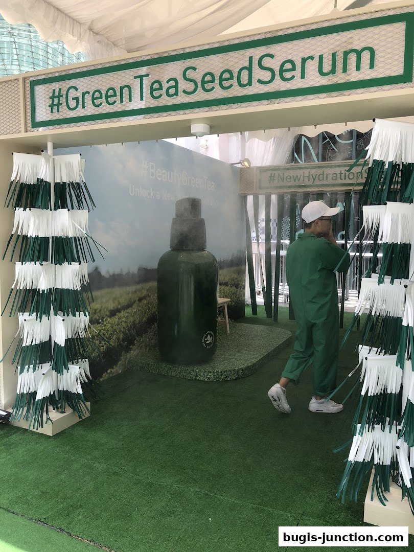 A promotional display for Innisfree's Green Tea Seed Serum with a large product bottle.