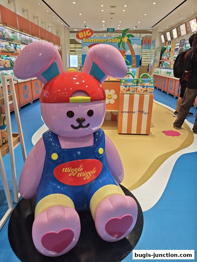 A large bunny mascot in overalls sits in front of an Innisfree store with a summer sale display.