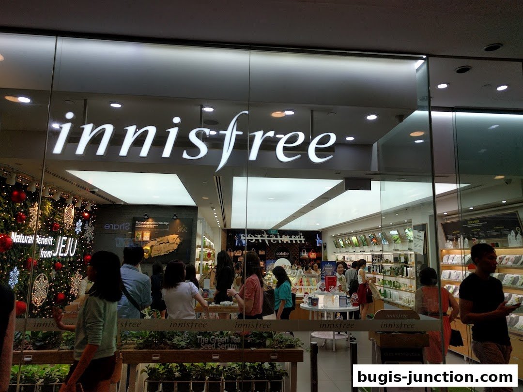 The Innisfree store front with a Christmas tree and customers browsing inside.