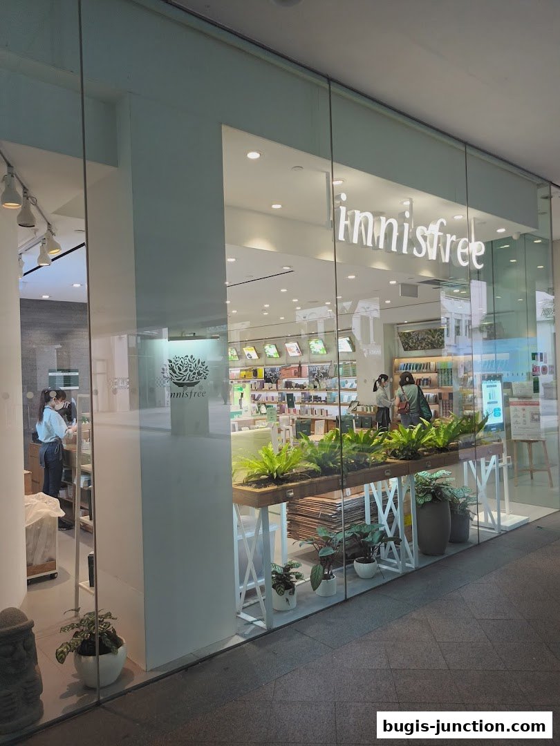 The exterior of the Innisfree Bugis Junction store, showcasing its products and a welcoming green display.