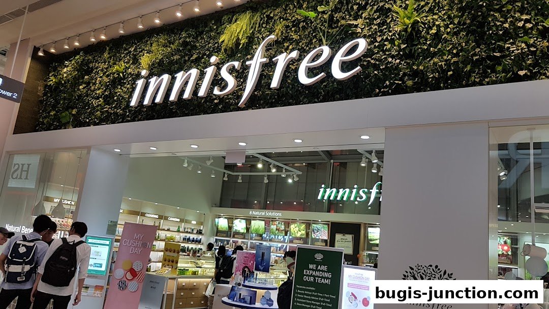 The exterior of an Innisfree store with a prominent green wall and illuminated logo.