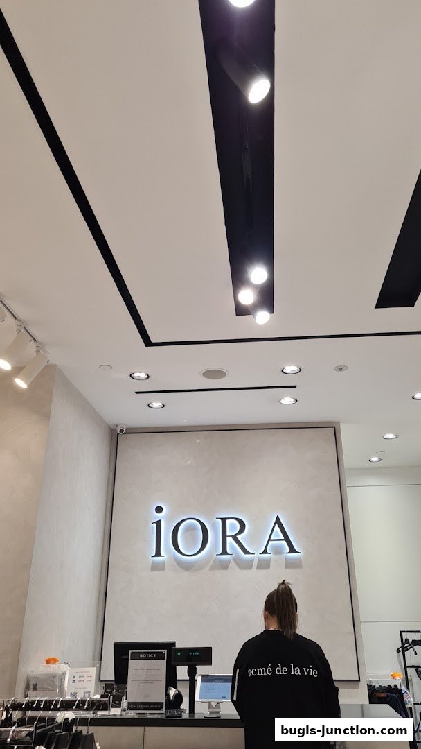 A person stands at the counter of the iORA Bugis Junction store, with the shop's logo visible.