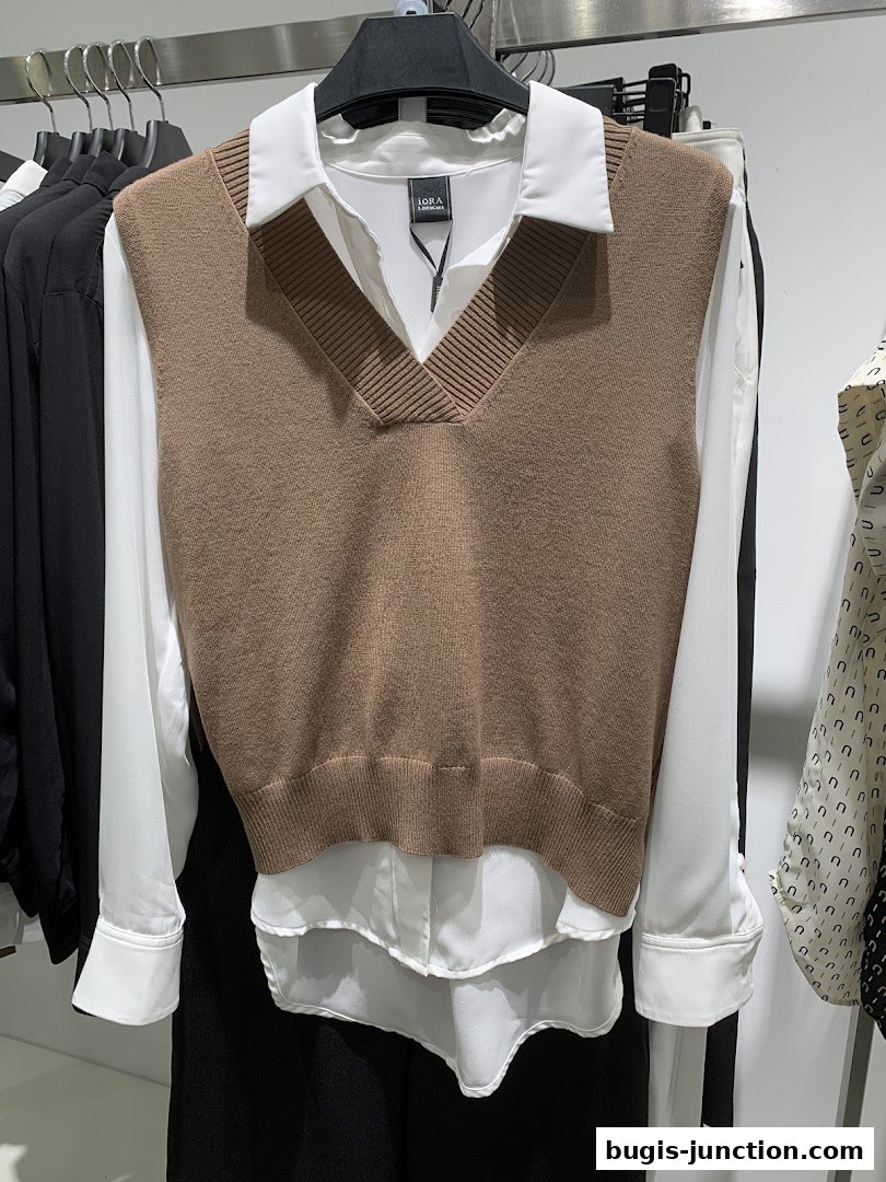 A brown knitted vest layered over a white collared shirt on a hanger.