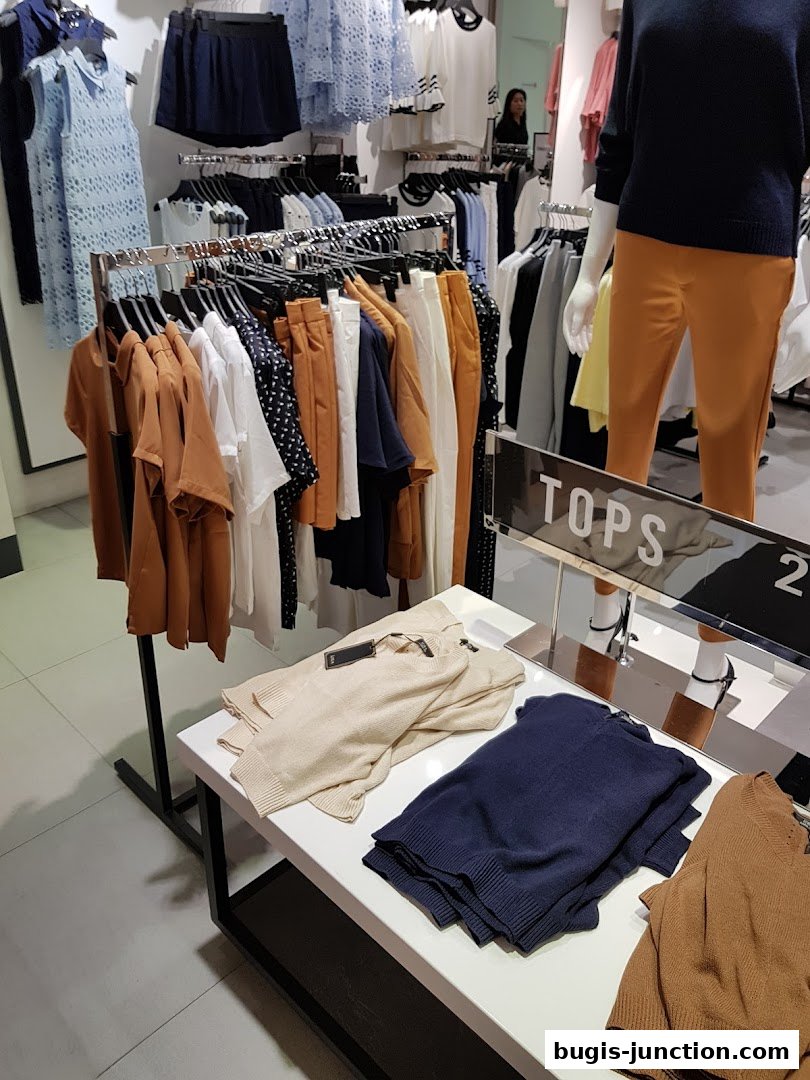 A retail store interior displaying a variety of women's clothing, including tops and bottoms.