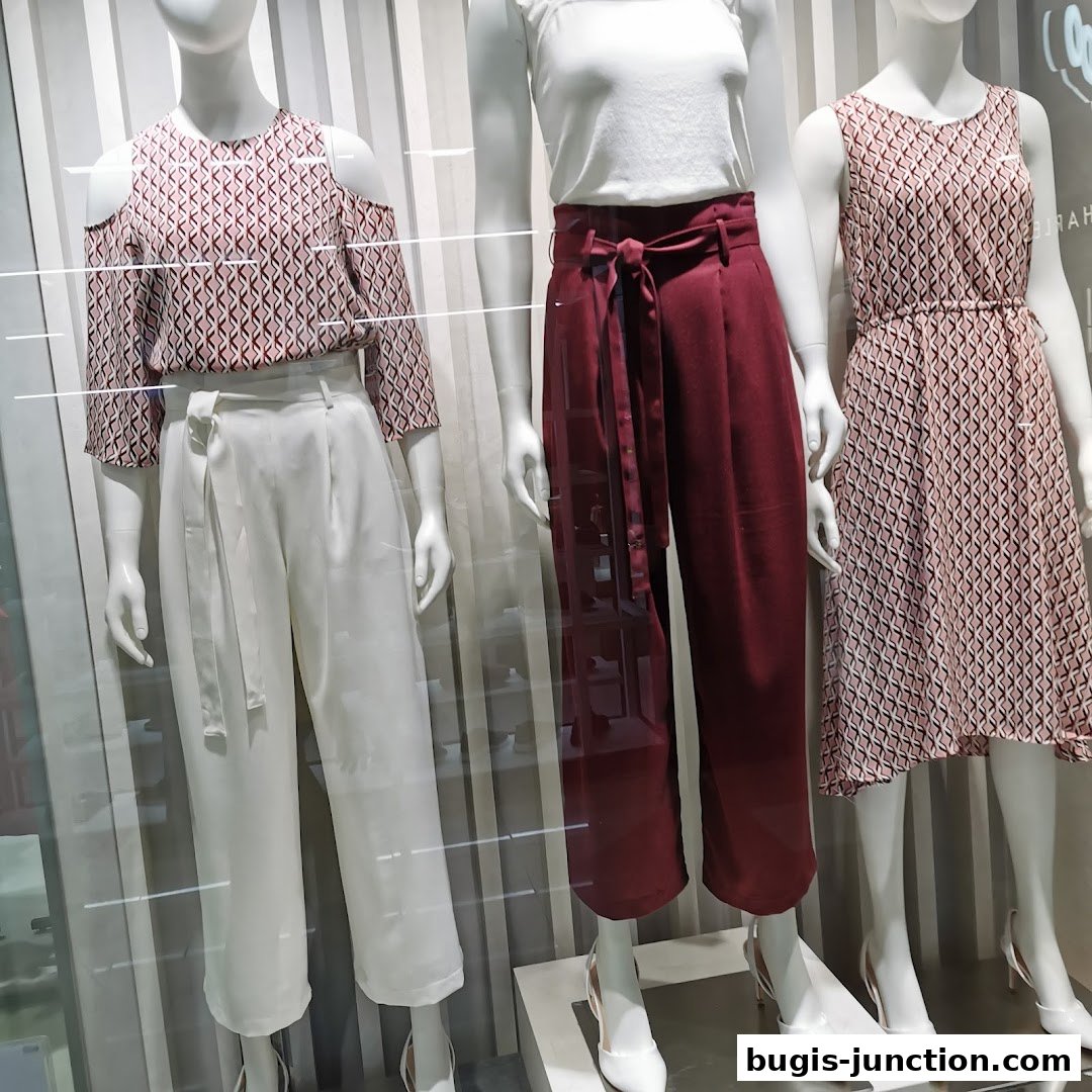 Mannequins display stylish women's fashion with patterned tops, wide-leg pants, and a dress.