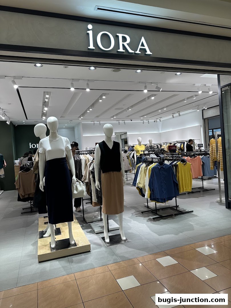 The iORA Bugis Junction shop front displays mannequins in stylish outfits and racks of colorful apparel.