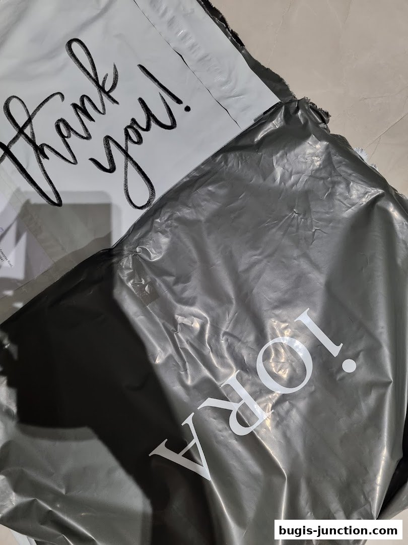 Two shopping bags, one white with 'thank you!' and a grey one with 'iORA' logo.
