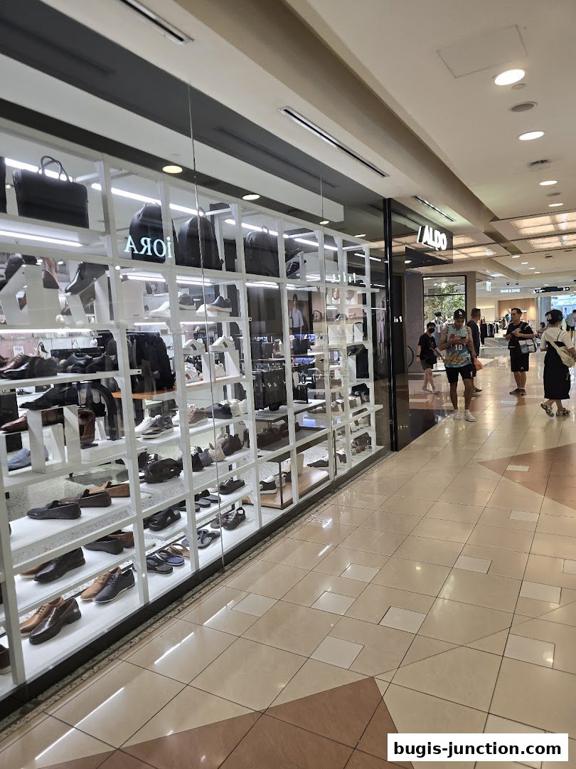 A well-lit shop displaying a wide variety of men's shoes and bags on shelves.