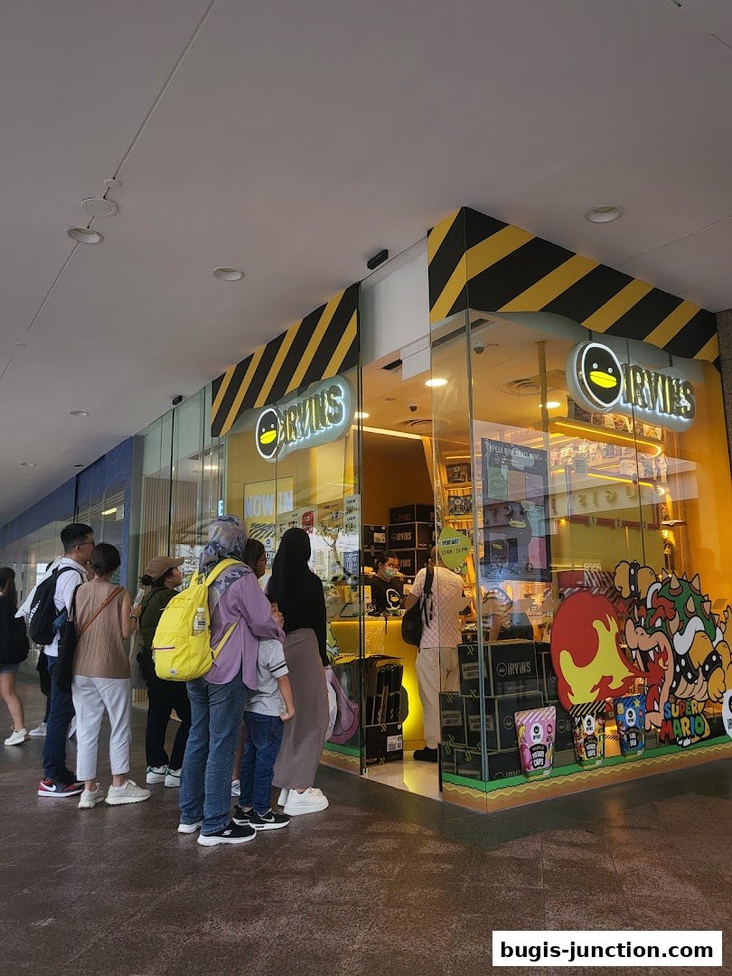 A line of customers waits outside the brightly lit IRVINS shop, featuring a Super Mario-themed display.