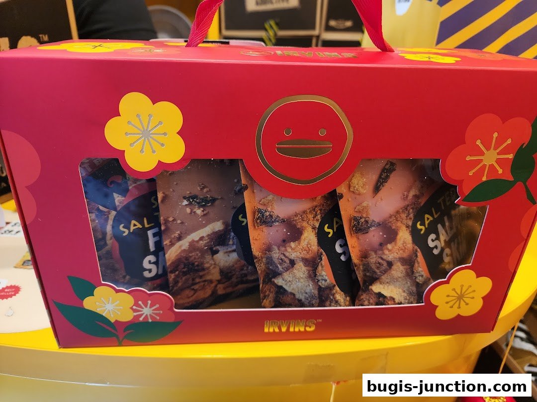 A red gift box from IRVINS filled with salted snacks, decorated with festive flowers.