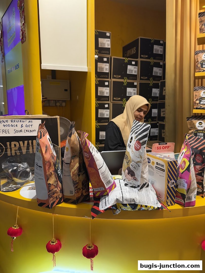 A shop counter displaying various snack bags and a staff member behind it.