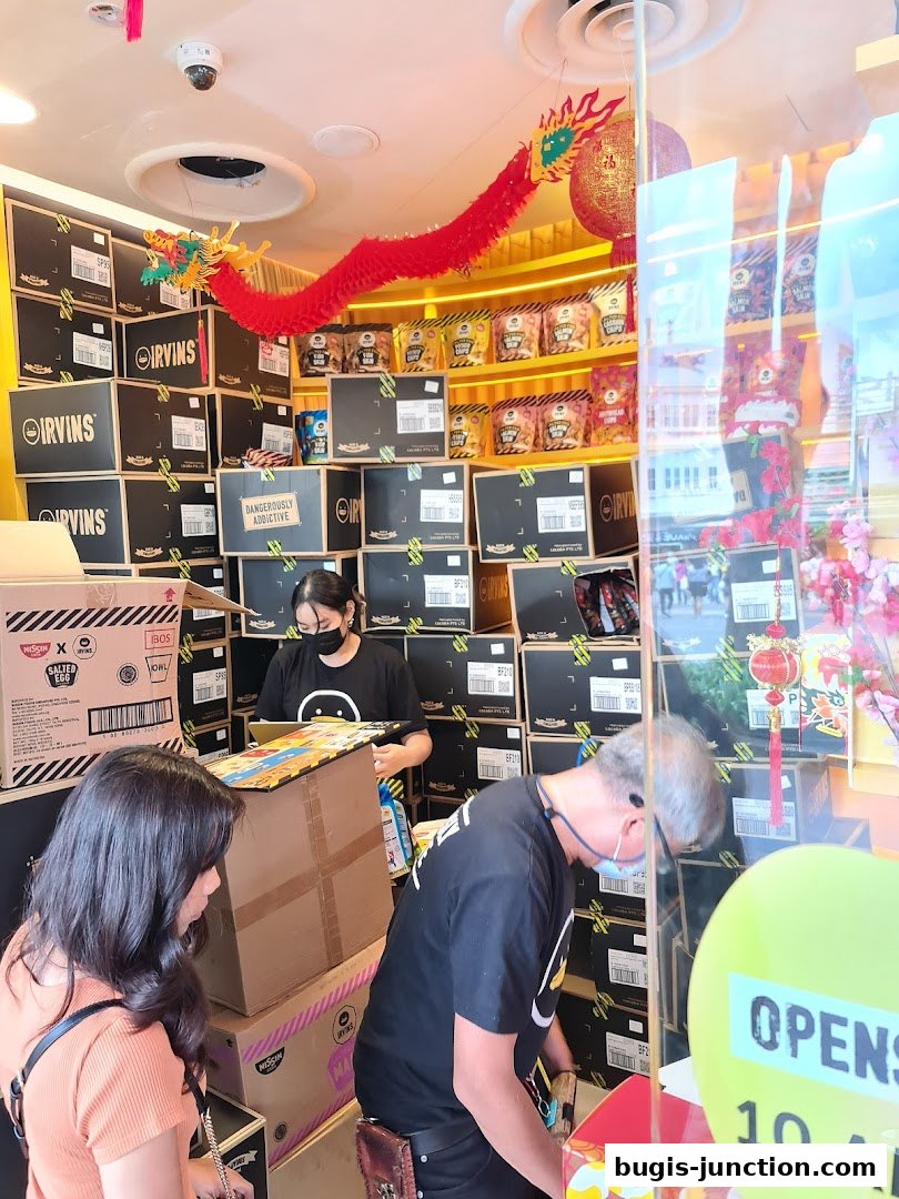 Customers and staff in a shop filled with boxes and snacks, decorated with a dragon.