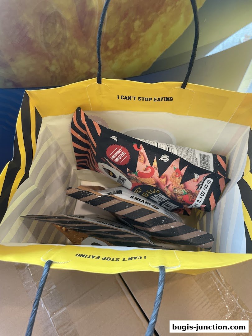 A yellow IRVINS shopping bag filled with snacks, featuring the slogan 'I CAN'T STOP EATING'.
