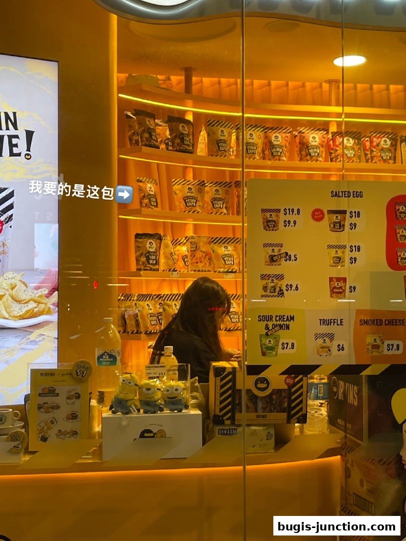 A brightly lit shop window displaying shelves of snacks and a price list.