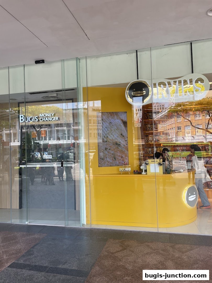 The IRVINS shop front with a bright yellow counter and a 'Bugis Money Changer' next door.