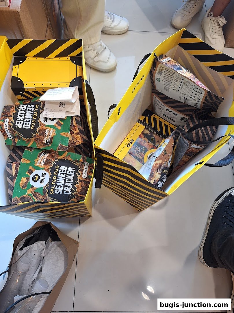 Shopping bags filled with IRVINS Salted Egg Seaweed Crackers and other snacks.
