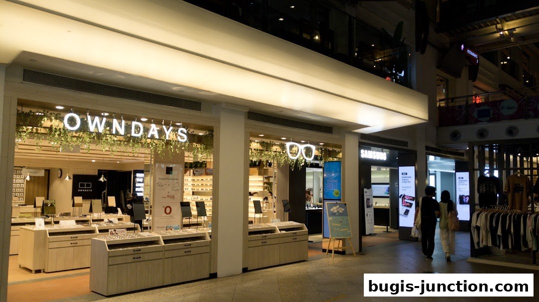 The exterior of an OWNDAYS optical shop with displays of eyeglasses and a Samsung store next door.