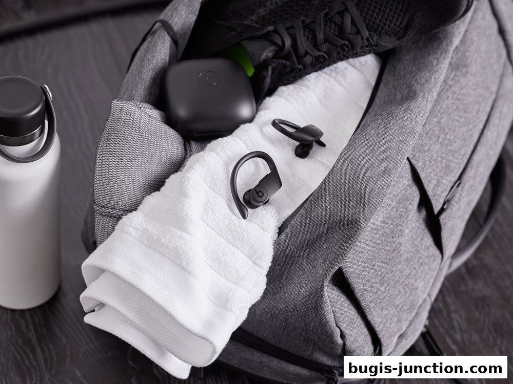 A gym bag packed with a water bottle, towel, earbuds, and sneakers.