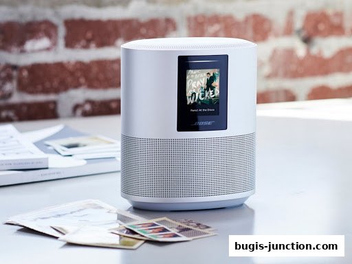 A white Bose smart speaker with a screen displaying album art and song title.