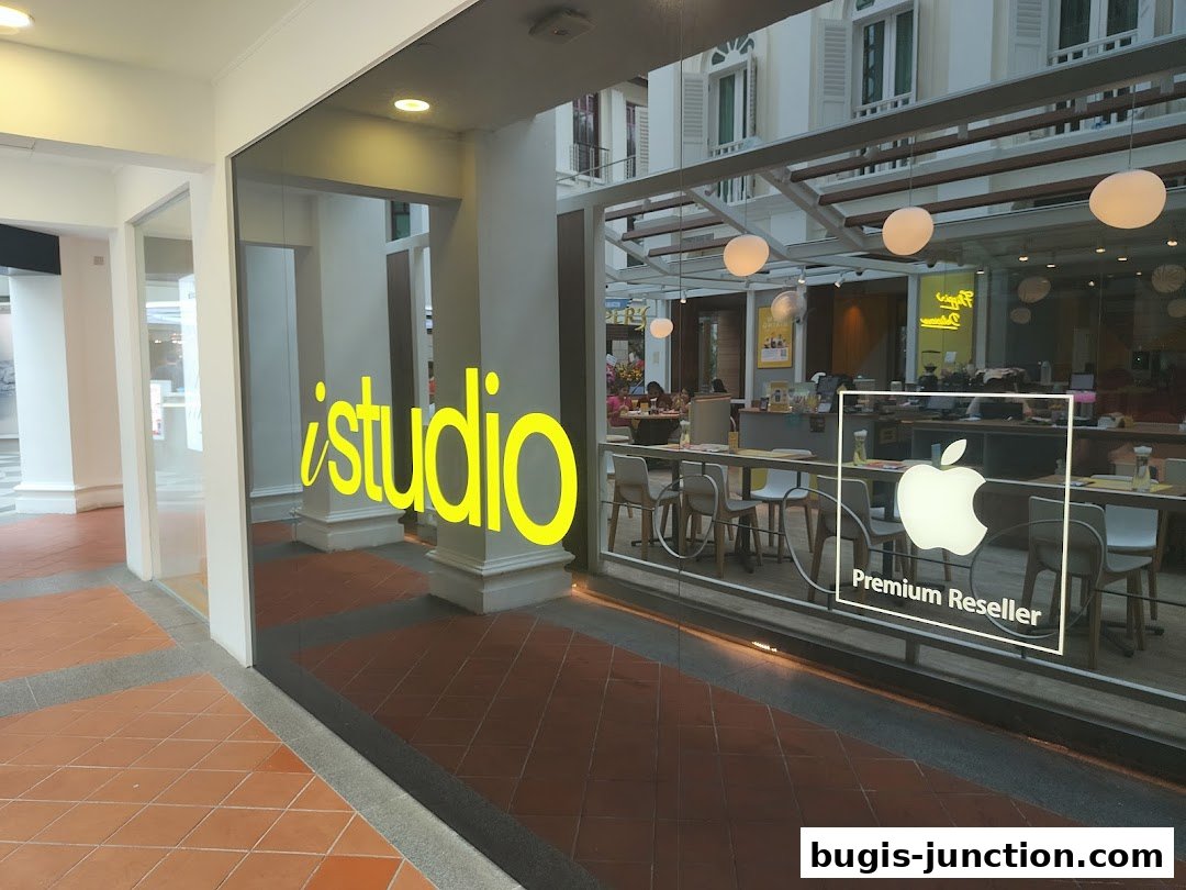 The iStudio Bugis Junction shop front with its prominent yellow logo and Apple Premium Reseller signage.