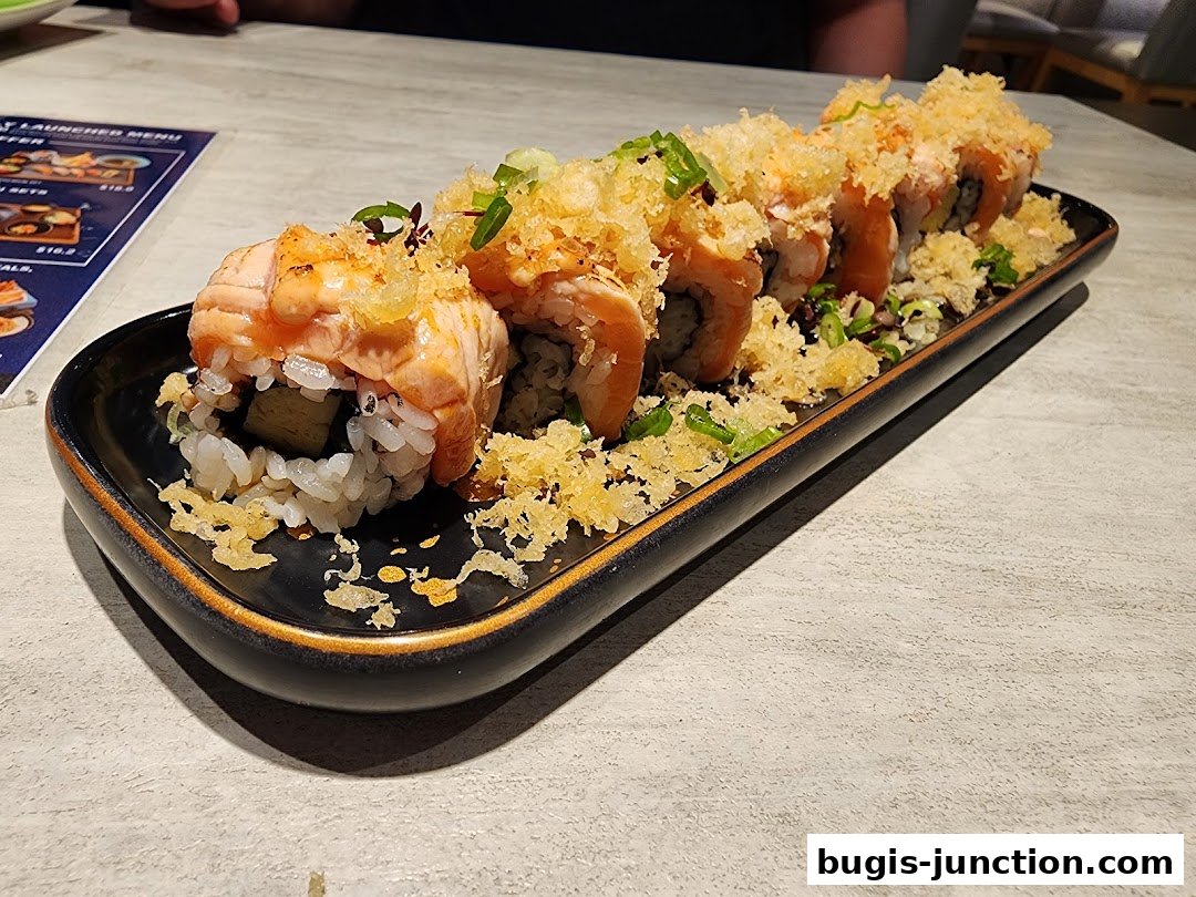 A platter of delicious salmon sushi rolls topped with crispy tempura flakes and green onions.