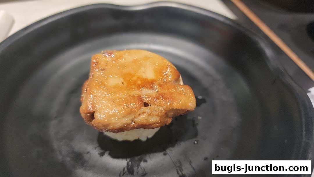 A close-up shot of a single piece of sushi with seared foie gras on top.