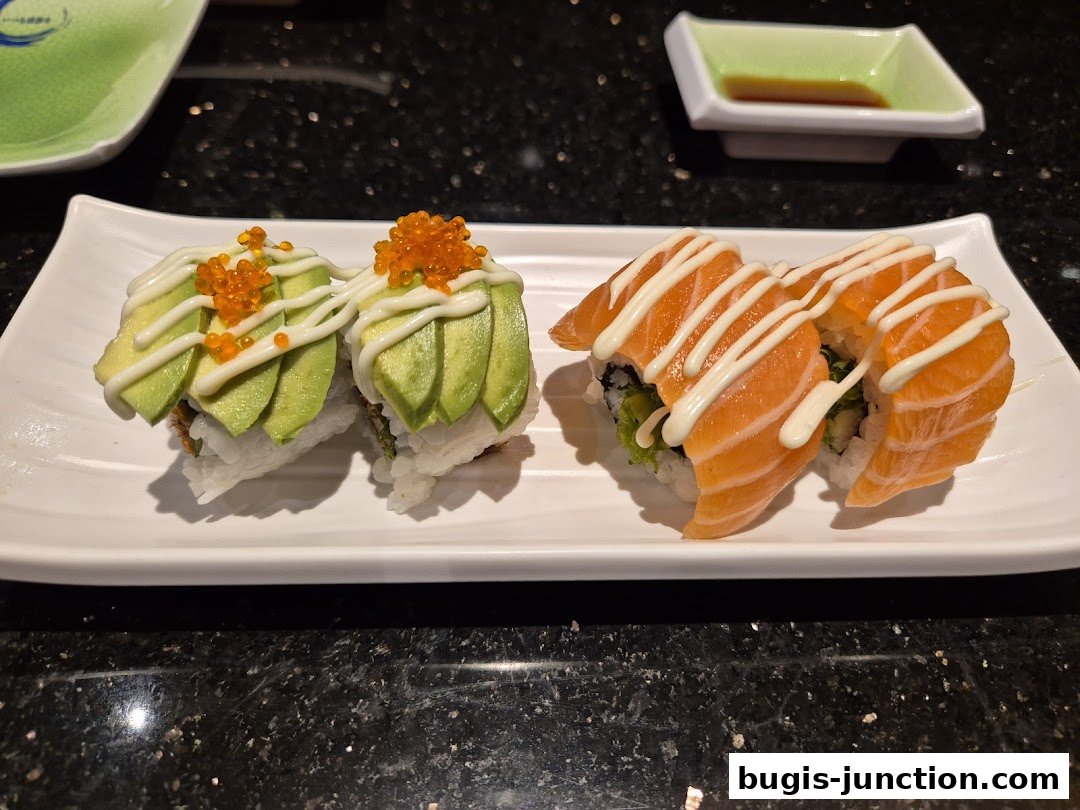 Two types of sushi rolls, one with avocado and roe, the other with salmon, served on a white plate.