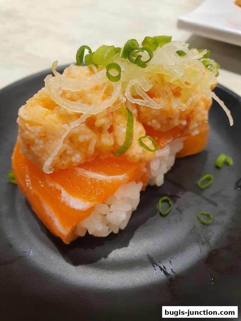 A close-up of delicious salmon sushi with a creamy topping and green onions.