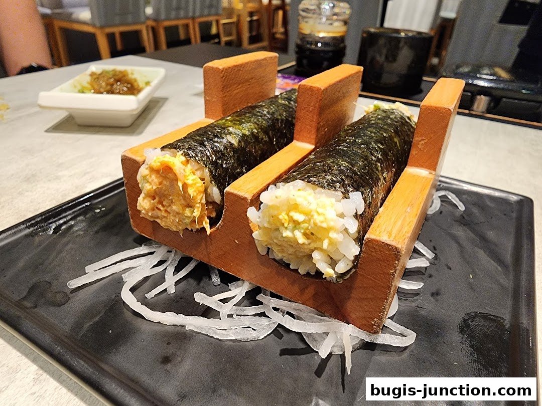 Two sushi rolls presented in a wooden holder on a black plate with shredded daikon.