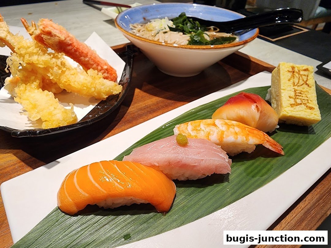 A platter of assorted sushi and tempura served with a bowl of soba noodles.