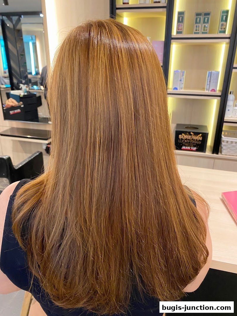 A person's long, reddish-brown hair with subtle highlights, styled in a salon.