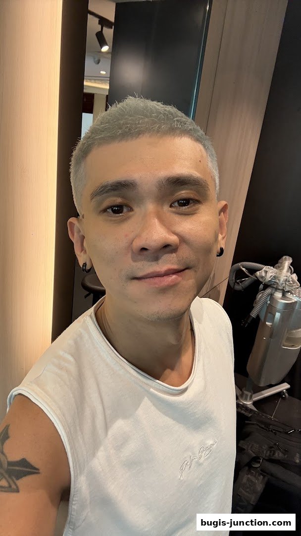 A man with short, light-colored hair and a white t-shirt smiles at the camera.